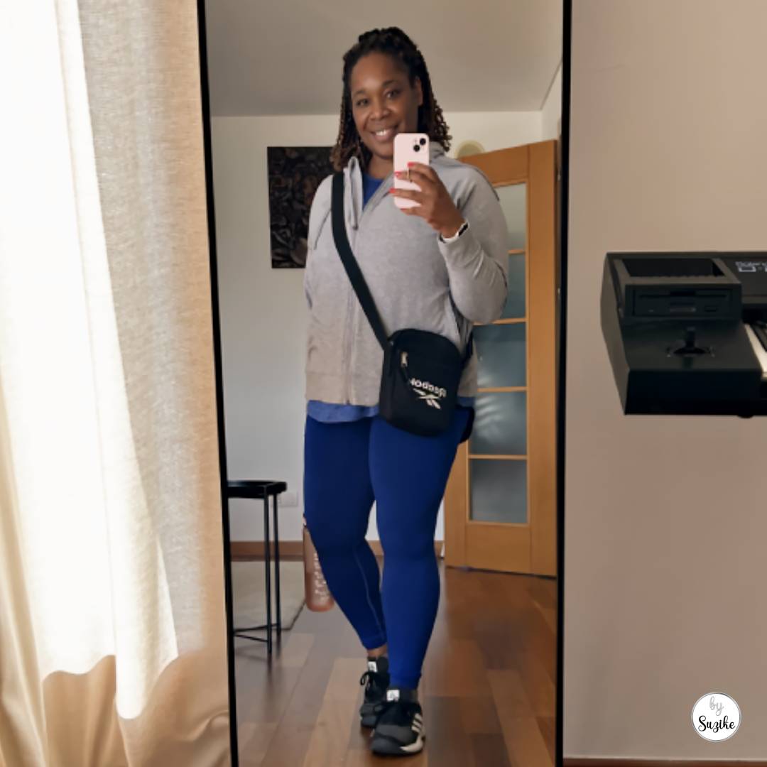 Suzike mirror selfie wearing a grey hoodie, blue leggings, trainers, and a black crossbody bag before a Les Mills Body Balance class in Portugal