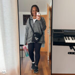 Smiling woman holding phone in mirror before a run — ready despite the cold.