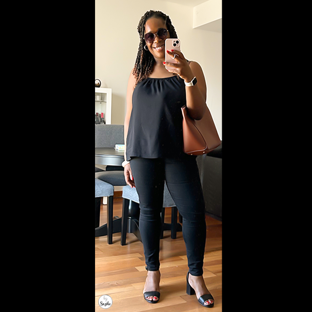 Suzike wearing an all black outfit for women, featuring a sleeveless Marks & Spencer top, black skinny jeans, black Clarks sandals, a brown Zara tote bag, oversized Afflelou sunglasses, Apple Watch, and pink phone case. Real-life summer style inspiration.
