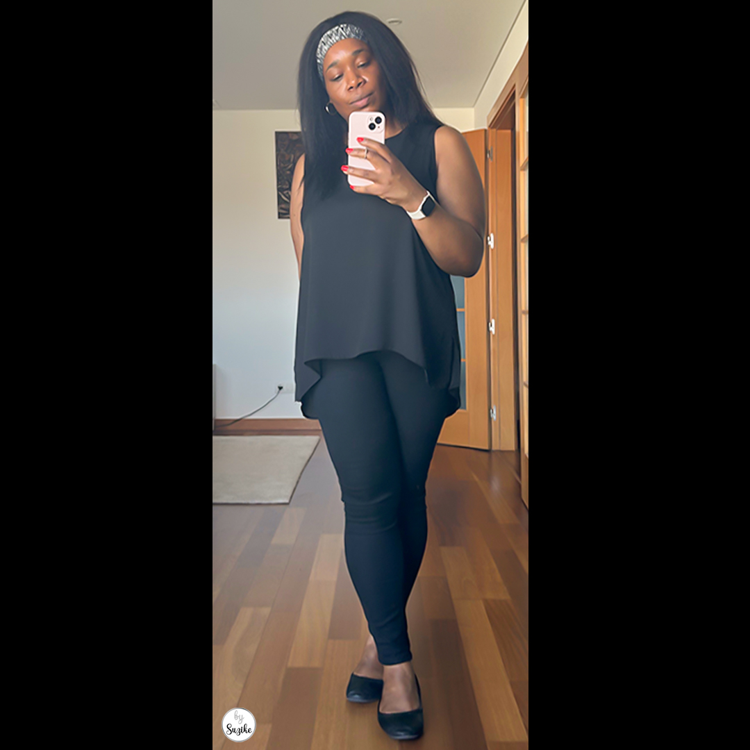 Full-body shot of a woman in a black sleeveless top and black skinny jeans, posing with confidence in an all-black casual look.