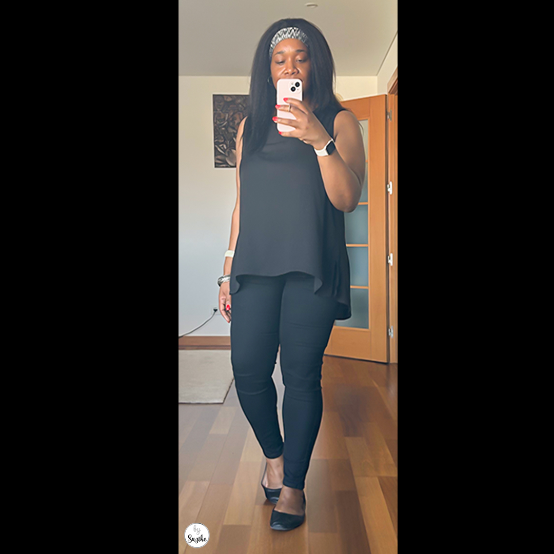 Woman dressed in a black sleeveless top and black skinny jeans, standing and showing a minimalist black outfit for women.