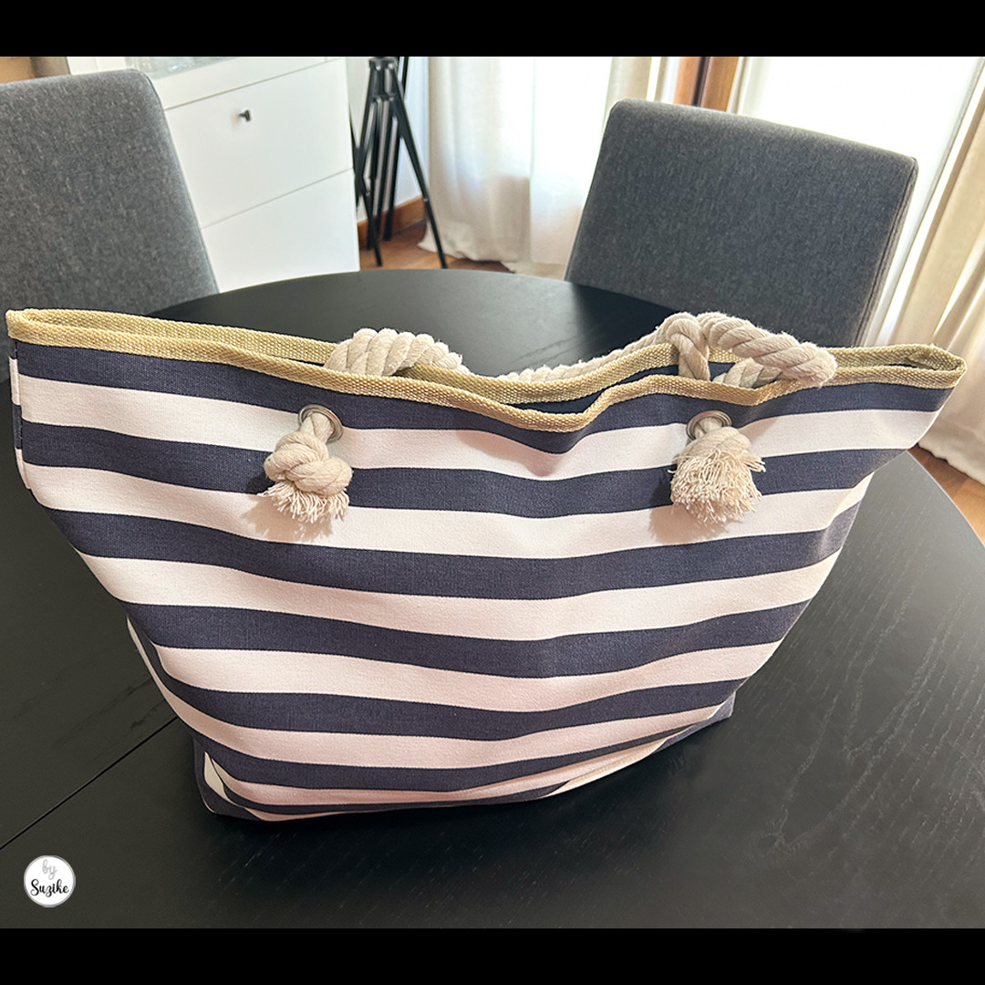 Large navy and white striped beach bag with rope handles on a black table – perfect beach bag for moms