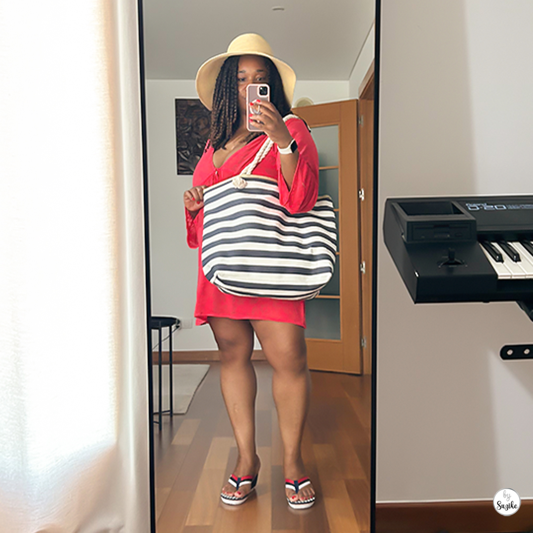Woman in red dress and summer hat holding navy and white striped beach bag in front of a mirror – real-life beach bag for moms