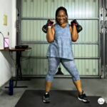 Woman holding two 12kg kettlebells at home gym, ready for a 20 minute kettlebell core workout.