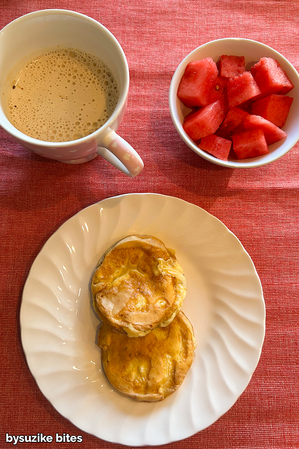 Day 2 weight loss journey breakfast – small omelettes on a white plate, with coffee and a bowl of fresh watermelon on a red tablecloth.