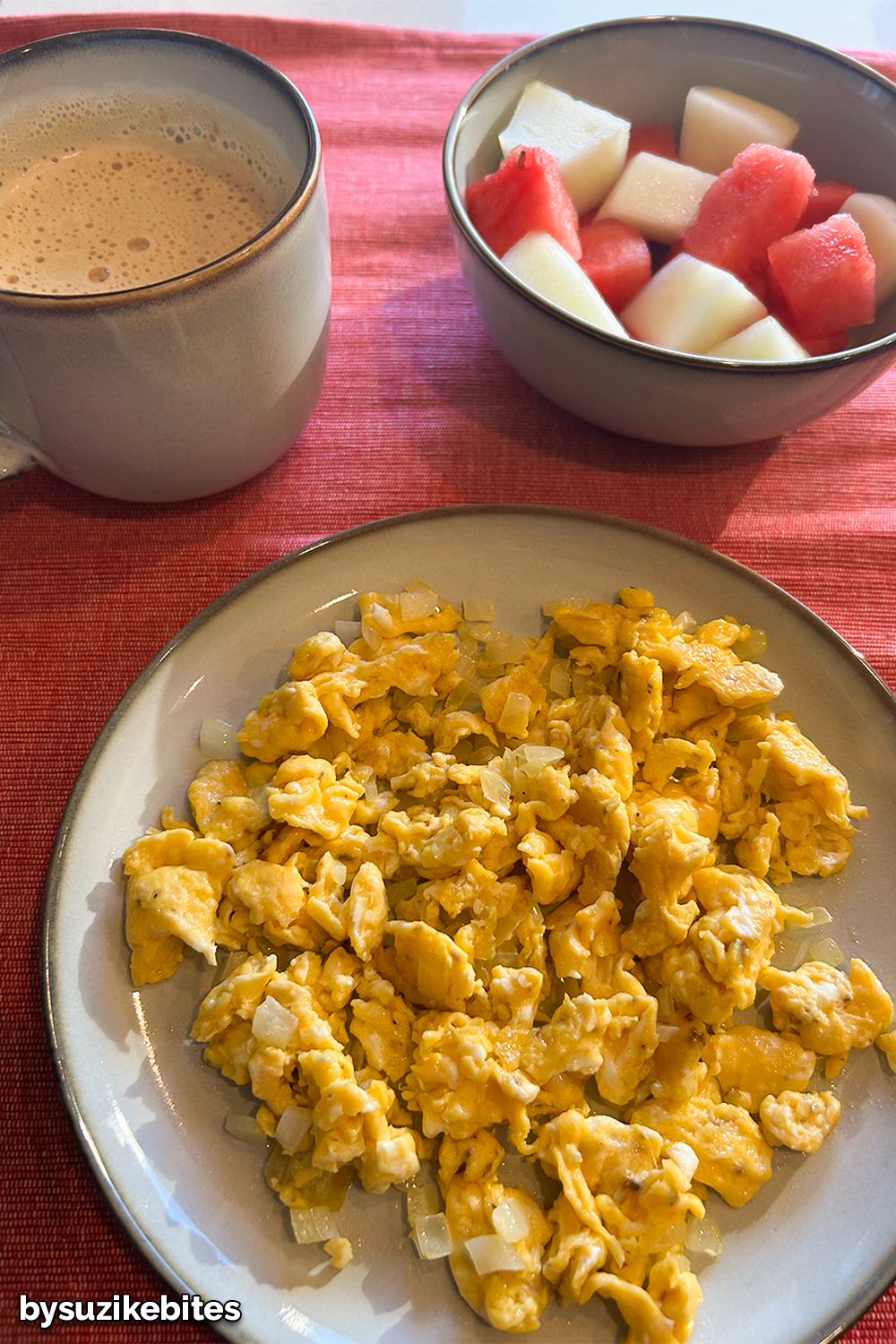 weight loss journey Day 1: Low carb breakfast with scrambled eggs, coffee and fresh fruit served on a red table.