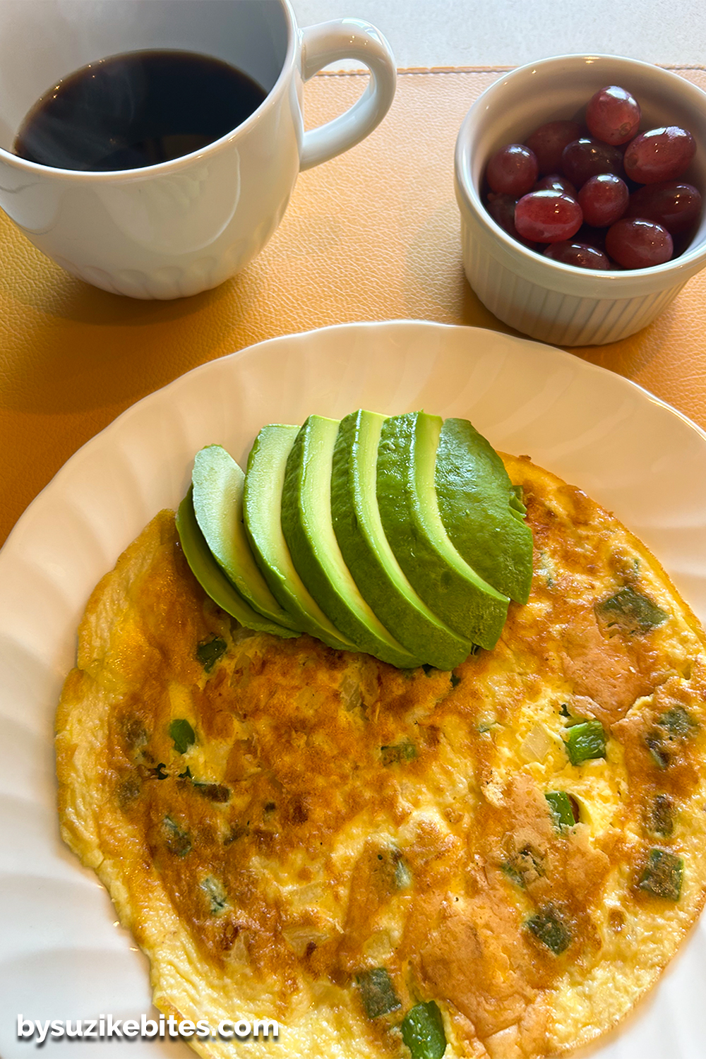 Healthy breakfast with an avocado omelette, fresh grapes, and black coffee, part of a balanced low carb meal for a weight loss journey.