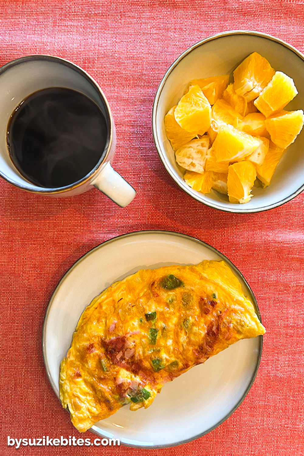 Healthy breakfast from my weight loss journey featuring a vegetable omelet, orange slices, and black coffee on a red tablecloth.