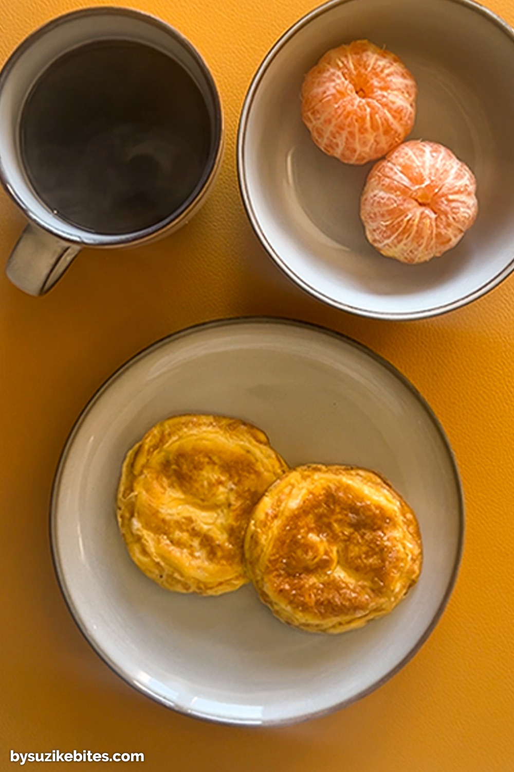Breakfast on Day 9 of my weight loss journey: egg muffins served with clementines and black coffee on a yellow background