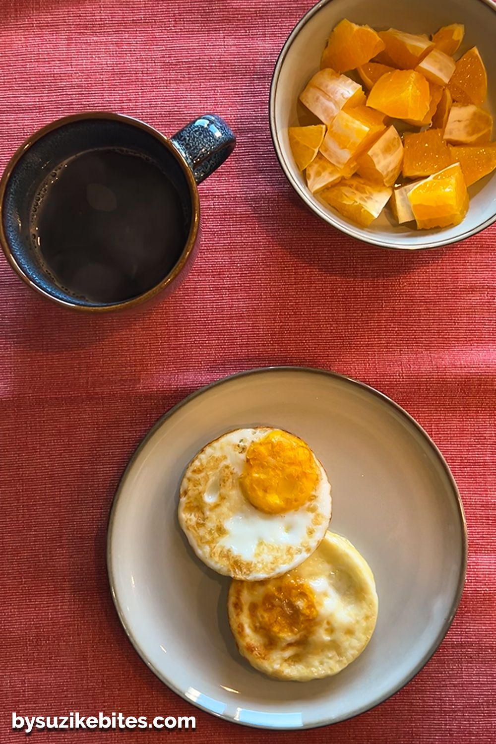 Healthy breakfast with egg bites, fresh orange pieces, and a cup of black coffee on a red placemat, part of a clean eating and weight loss journey.
