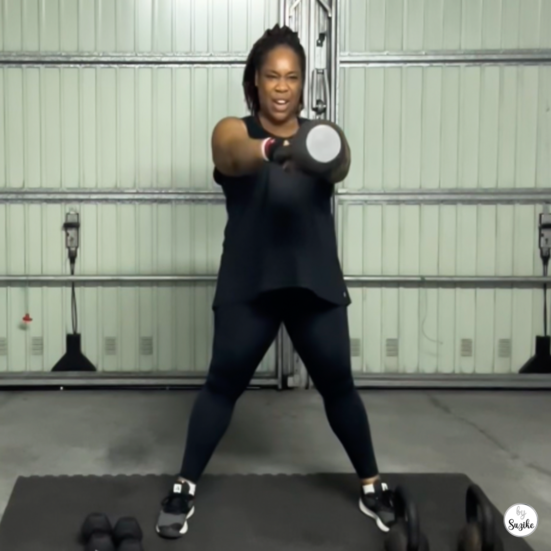 Woman training in a home gym with a kettlebell, mid-workout stance, focused expression, indoor lighting, minimal background.