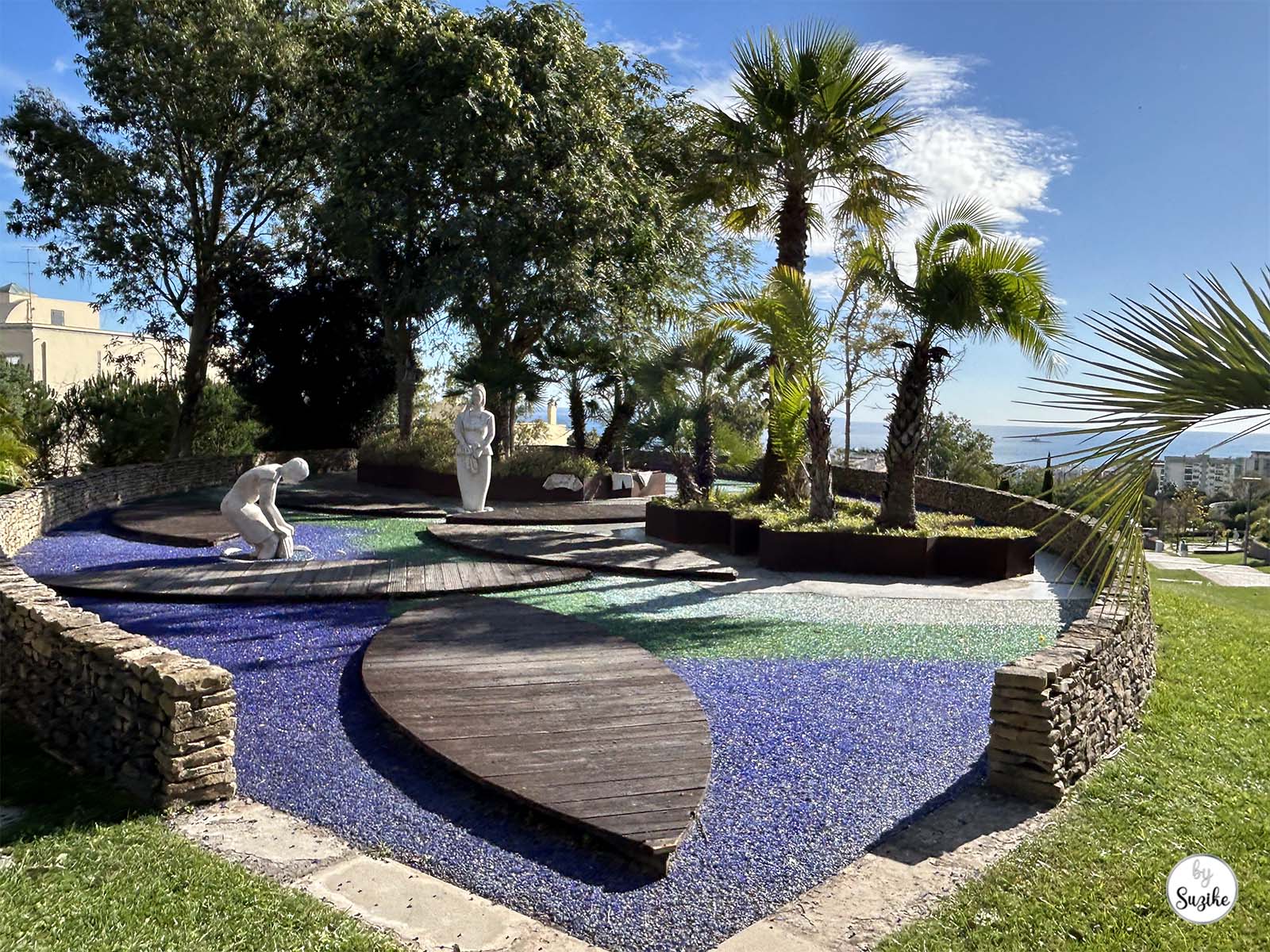 Sunny garden area with blue mosaic patterns and palm trees at the Park of the Poets in Oeiras