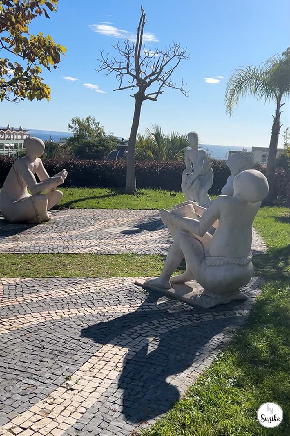 Stone sculpture and cobblestone path surrounded by greenery at the Park of the Poets in Oeiras