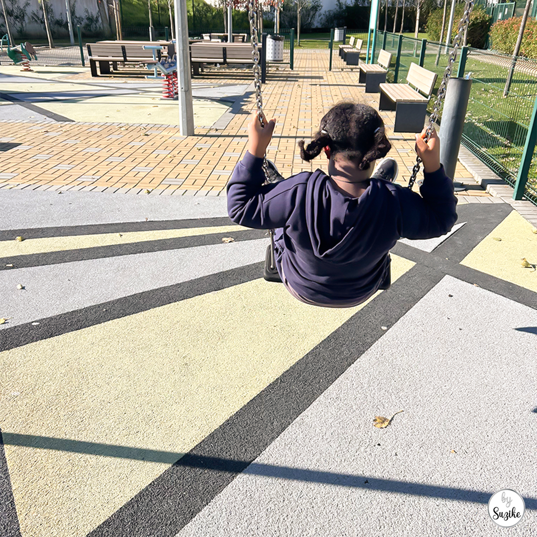 hild swinging at a playground on a warm sunny day