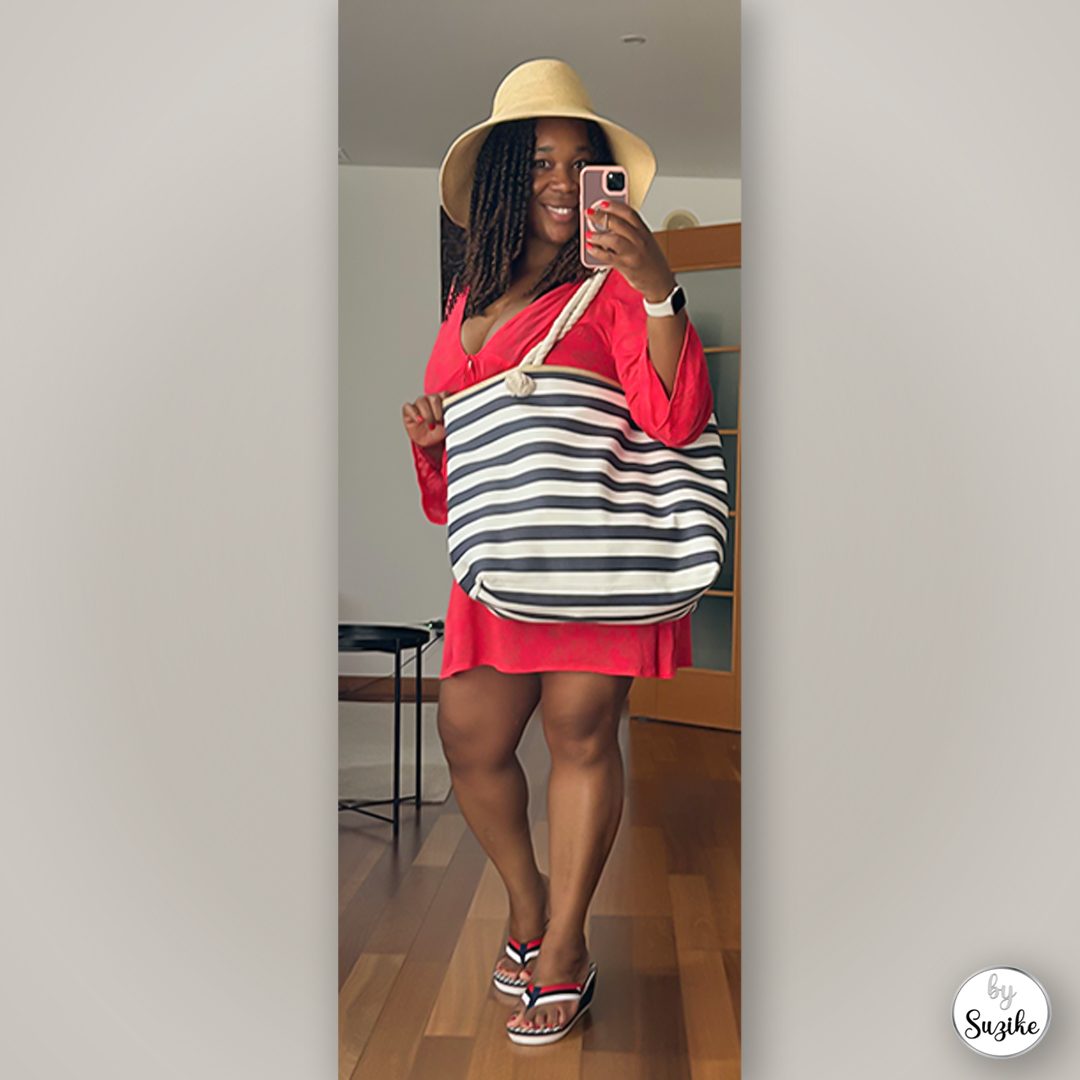 Side pose of Suzike in a red summer dress with a striped tote bag and sandals, real-life red summer dress outfit.