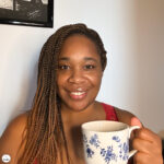 Woman smiling warmly while holding a mug, capturing a calm Me Time moment