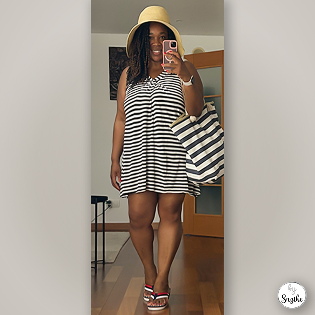 Full-body mirror selfie of Suzike wearing a beach striped dress, summer hat and striped tote bag for a casual summer look.