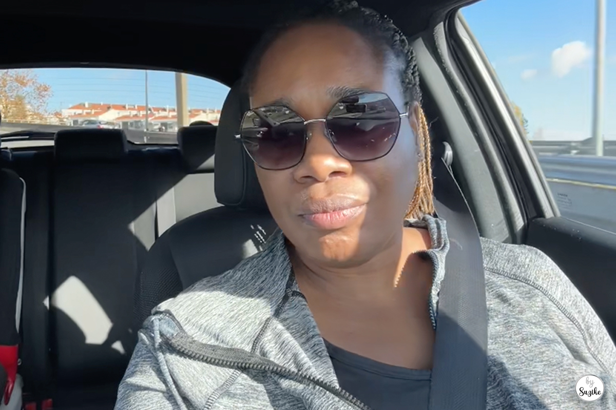 Suzike driving home after finishing her quick grocery run, wearing sunglasses in the afternoon light.