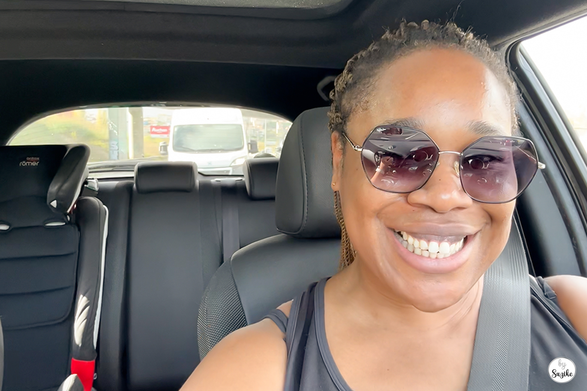 Suzike smiling inside her car while driving to Auchan for a quick grocery run.