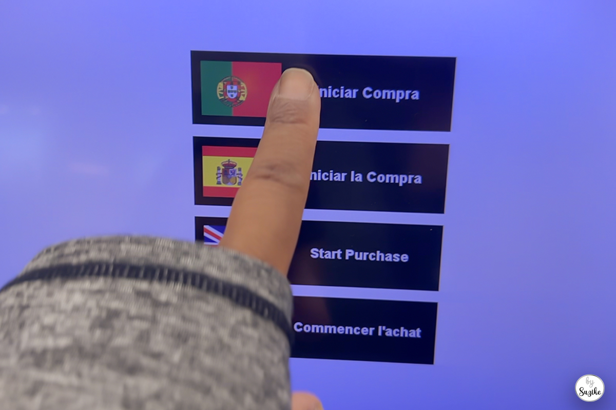 Suzike selecting the Portuguese language on the self-checkout screen during her quick grocery run.