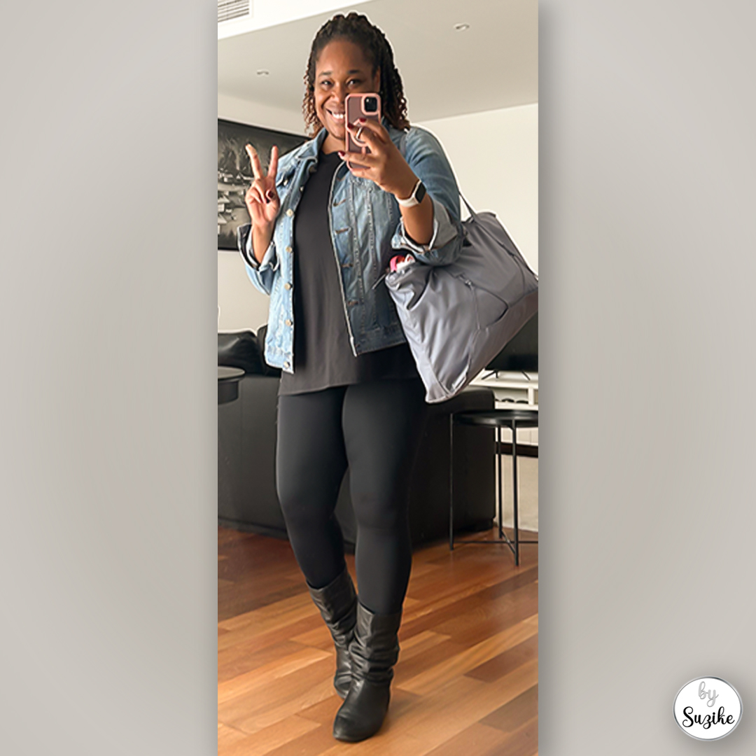 Full-body mirror selfie of a woman wearing a denim jacket, black top, leggings and black boots with a large grey tote bag on her shoulder.
