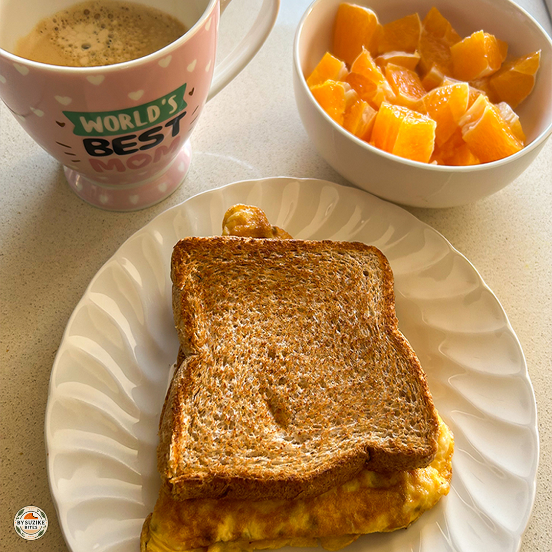 Real-life breakfast idea: egg toast with orange and coffee on a plate, with a mug of coffee and a bowl of fresh orange pieces.