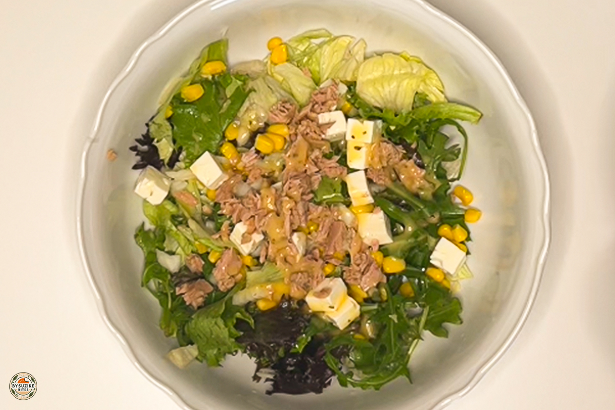 0-minute feta and tuna salad in a bowl with lettuce, corn, feta cubes, sliced onion, and tuna