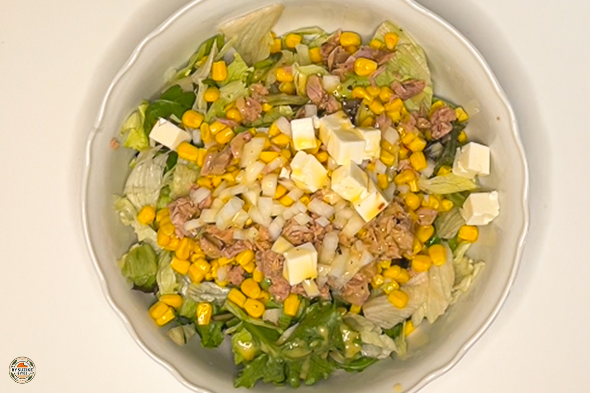 Close-up of 10-minute feta and tuna salad showing tuna flakes, feta, corn, and greens before tossing