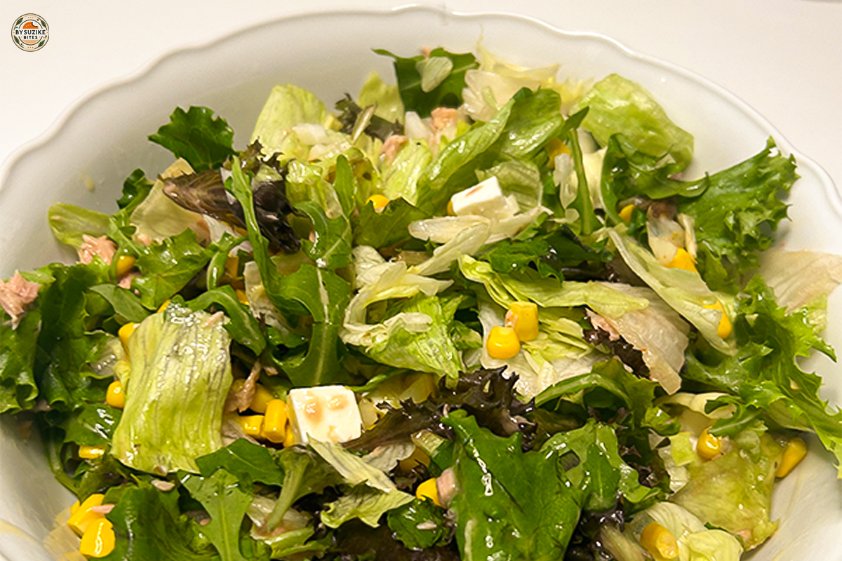 10-minute feta and tuna salad in a bowl with mixed lettuce, corn, feta cubes, and sliced onion