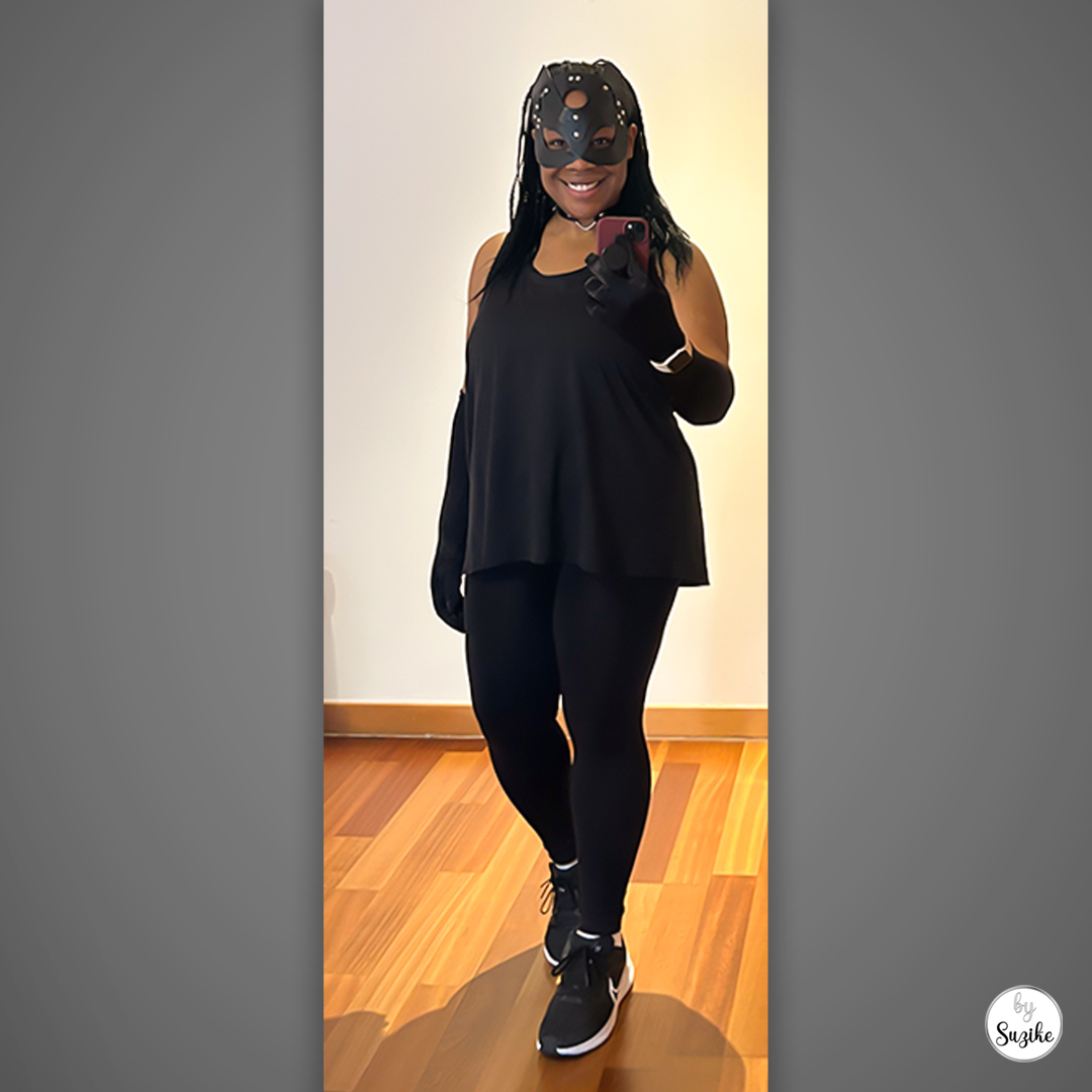 Catwoman costume for women full body look with black cat mask, long black gloves, and an all-black outfit with trainers.