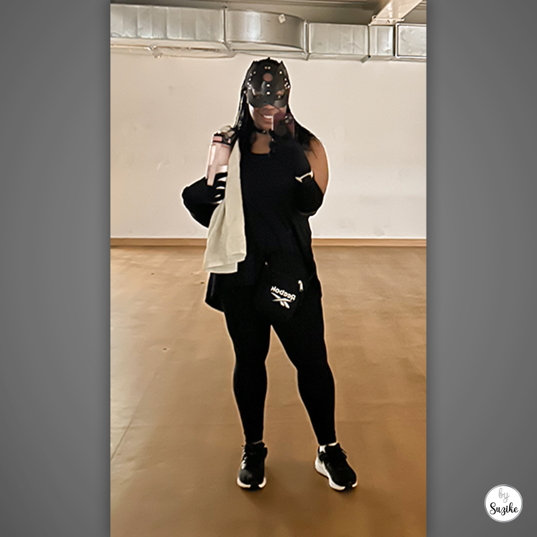 Catwoman costume for women full outfit with black cat mask and long black gloves, wearing an all-black look with trainers and a bag.