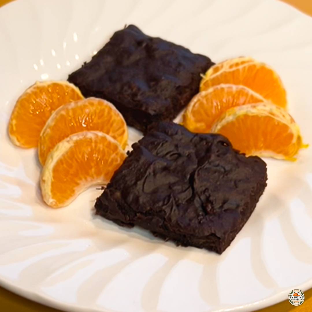 Chocolate banana brownies served with orange slices on a plate.