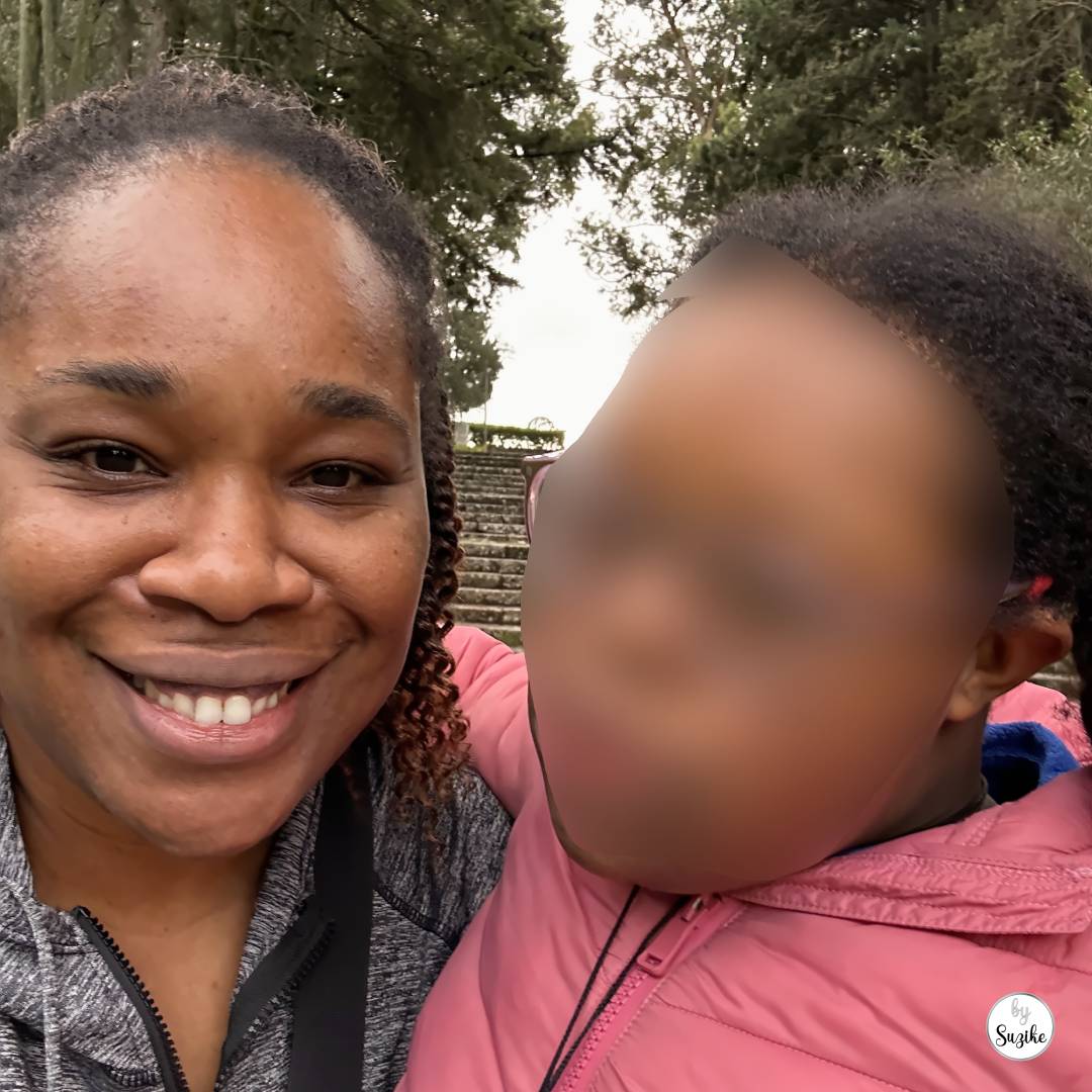Morning walk routine over 40: Selfie of Suzike holding Felisberta at Estádio Universitário de Lisboa, with stone steps and trees behind them.