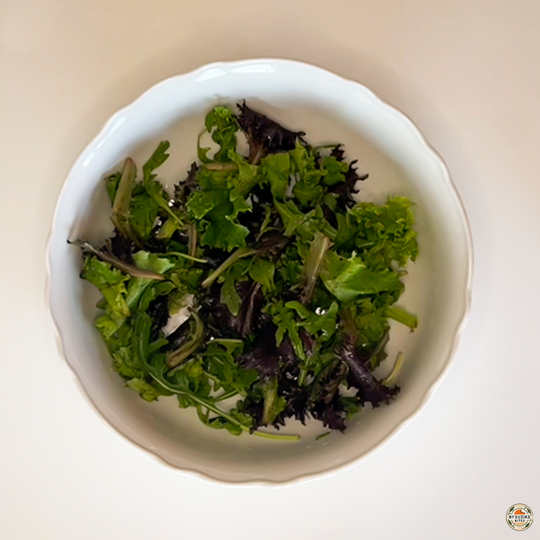 Egg salad with feta and mozzarella starting with a mixed lettuce base in a white bowl.