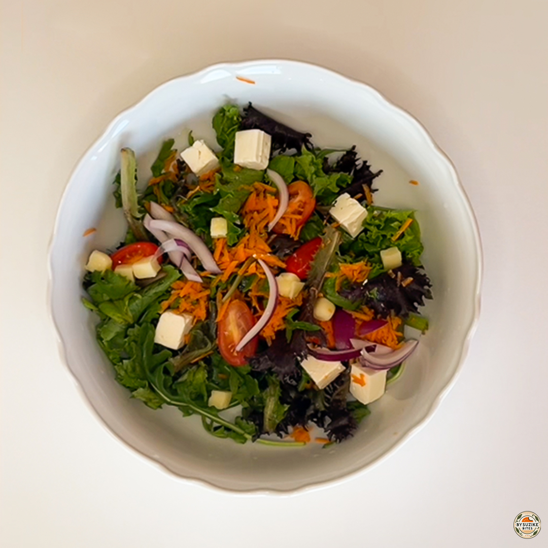 Egg salad with feta and mozzarella with sliced red onion added to mixed greens, tomatoes, and cheese.