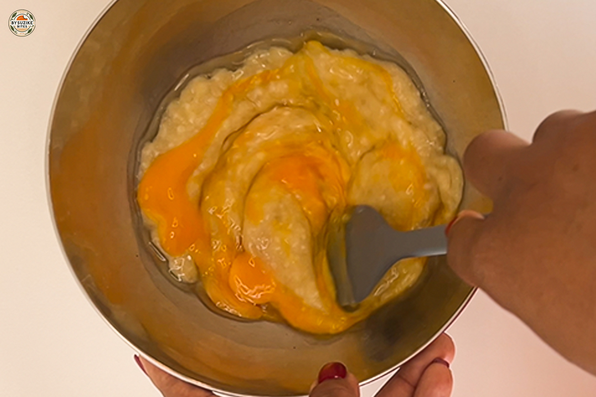 Mixing eggs into mashed banana for fluffy banana oat cake.