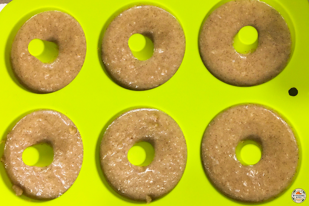 Keto cinnamon donut batter piped into a silicone donut pan before baking