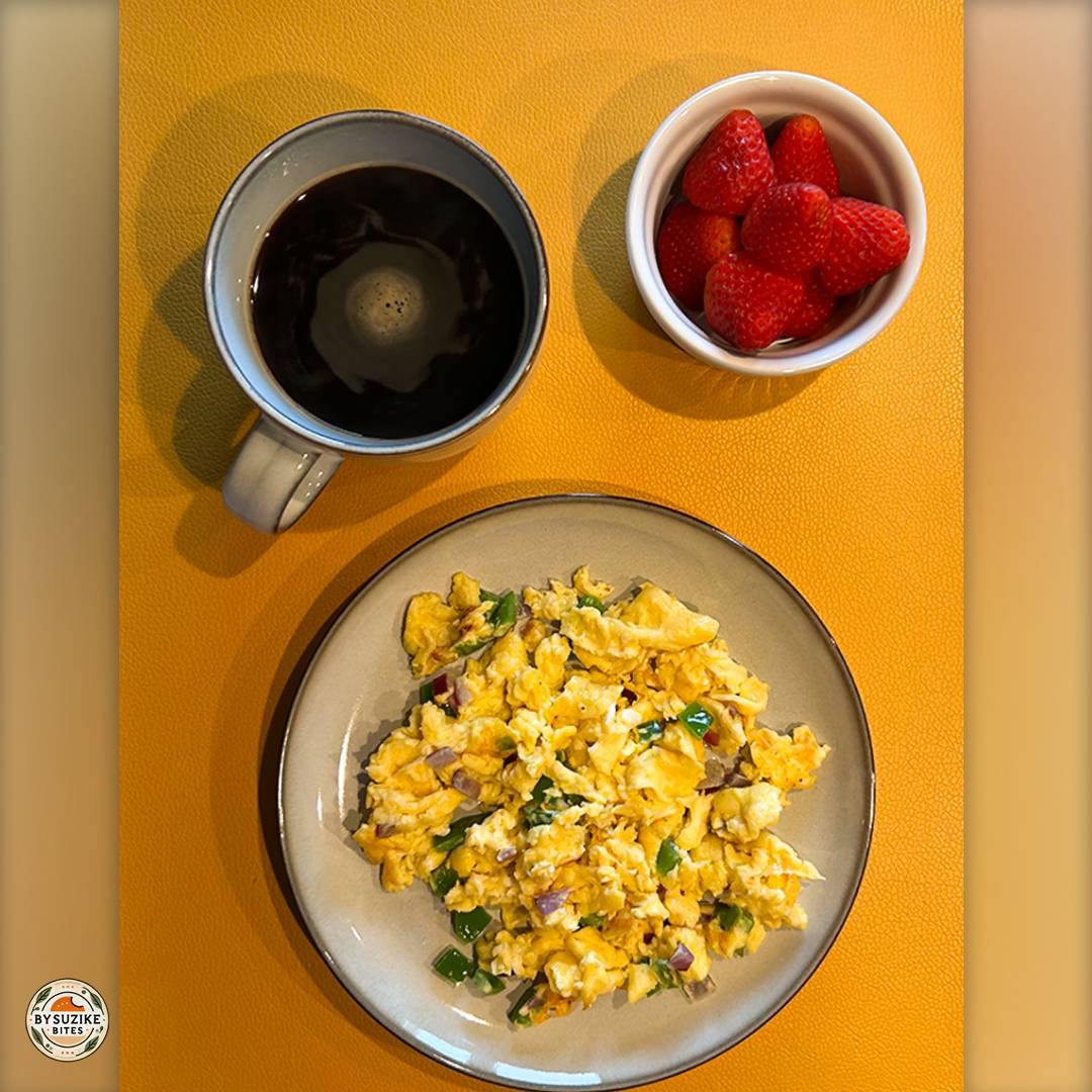 low carb breakfast idea: Plate of scrambled eggs with red onion and parsley, with strawberries and a cup of espresso on the side.
