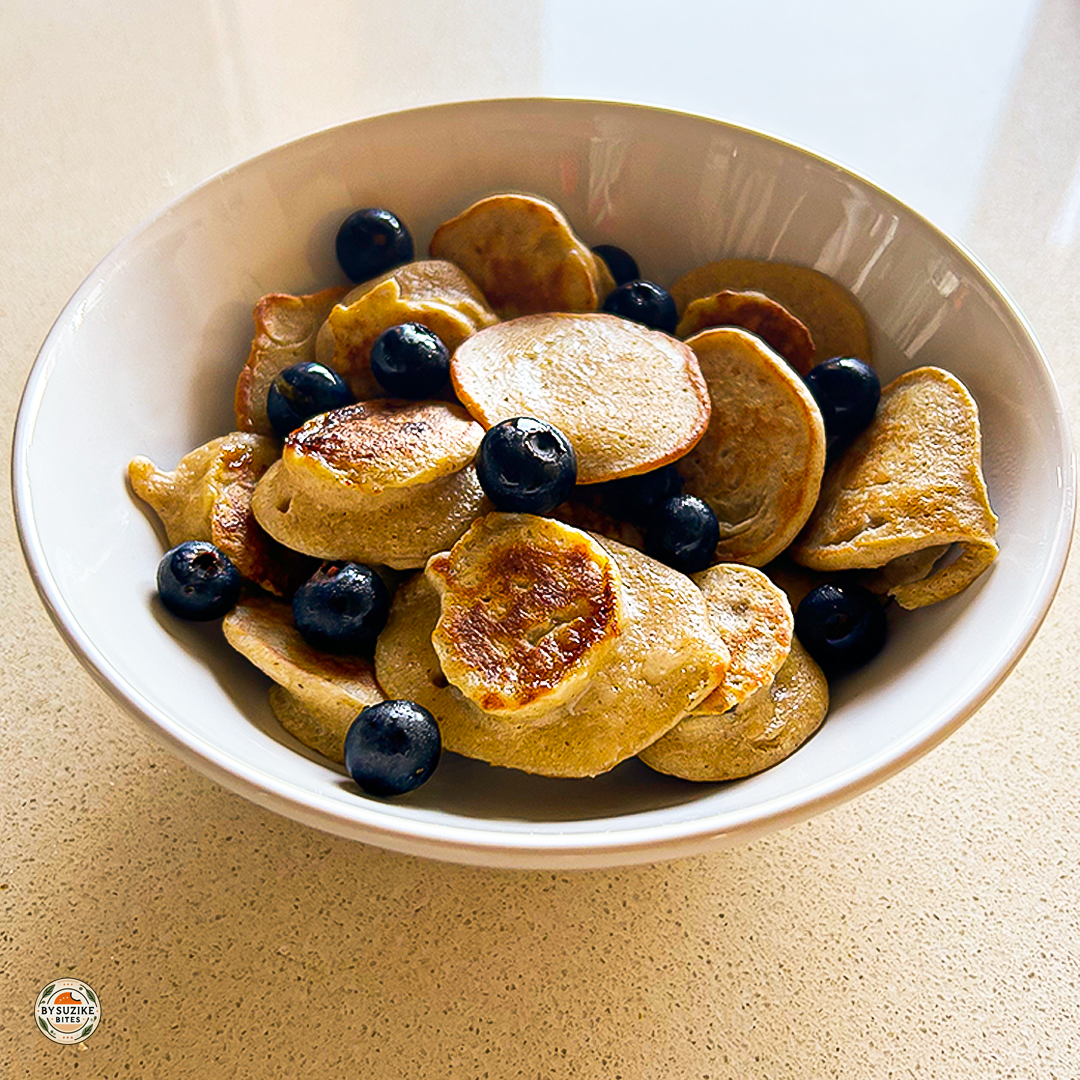 Mini oat and banana pancakes served in a bowl with fresh blueberries