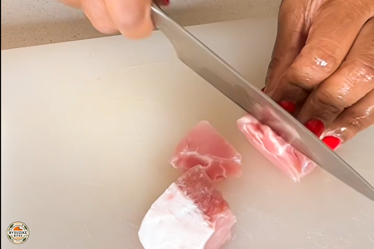 Step 1: Cutting fresh pork into small cubes for the okra stew