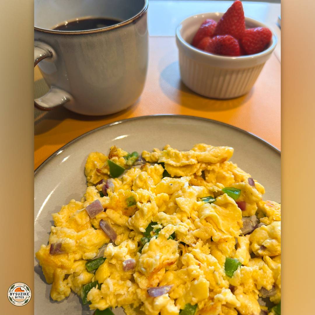 low carb breakfast idea: Plate of scrambled eggs with red onion and parsley, with strawberries and a cup of espresso on the side.