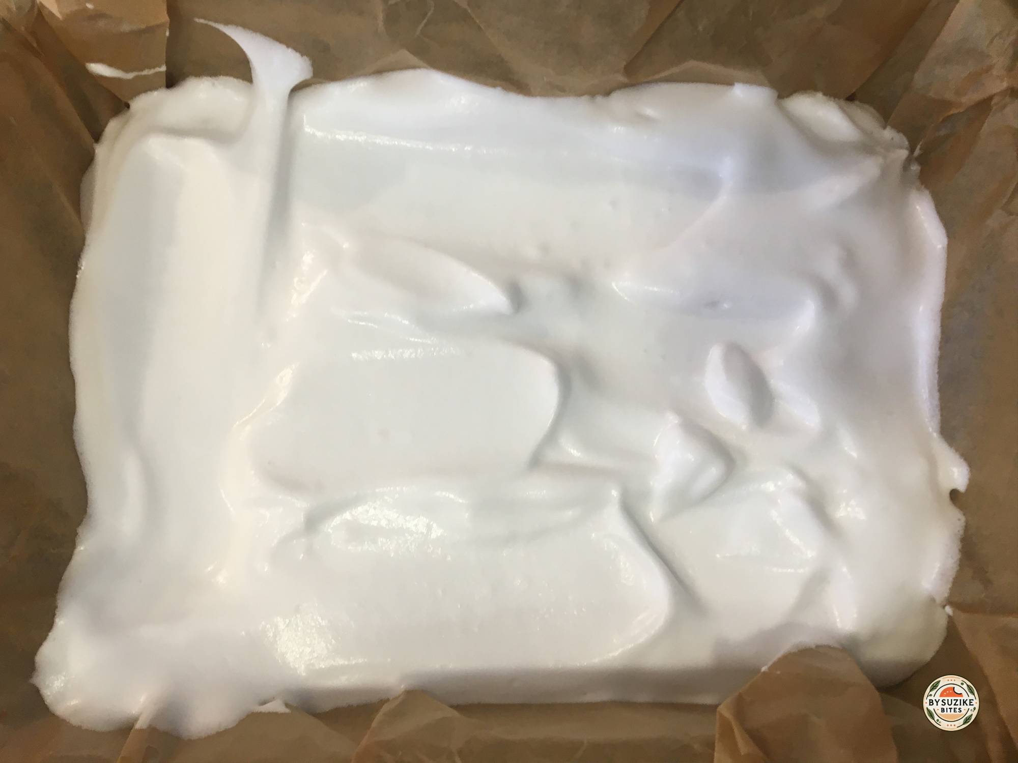 Keto marshmallow mixture poured into a parchment lined pan before chilling.