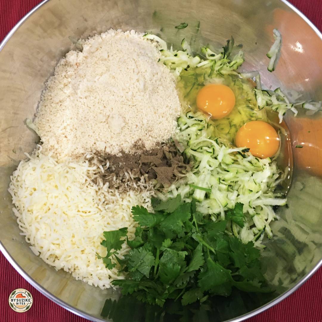 Keto zucchini tots ingredients with seasoning added before mixing.