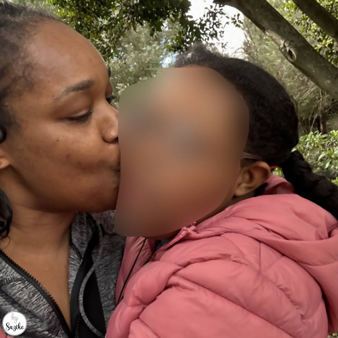Mother kissing her daughter on the cheek during an outdoor walk