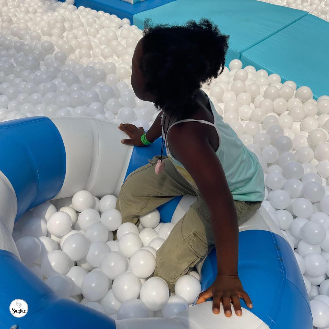 Kids’ activities before parents go on holiday with a child playing in a ball pit during a summer family activity.