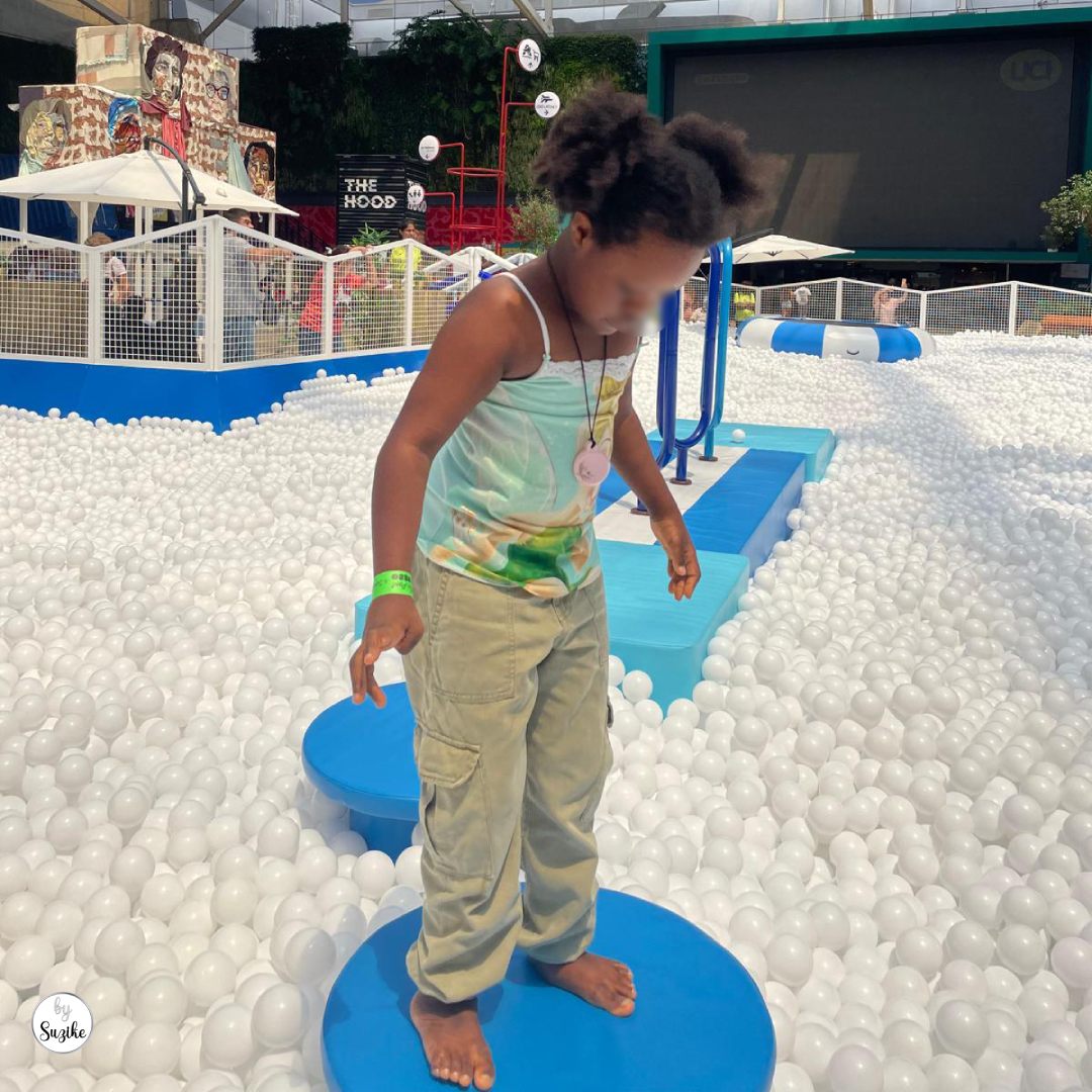 Kids’ activities before parents go on holiday with a child playing in a ball pit during a fun summer activity.
