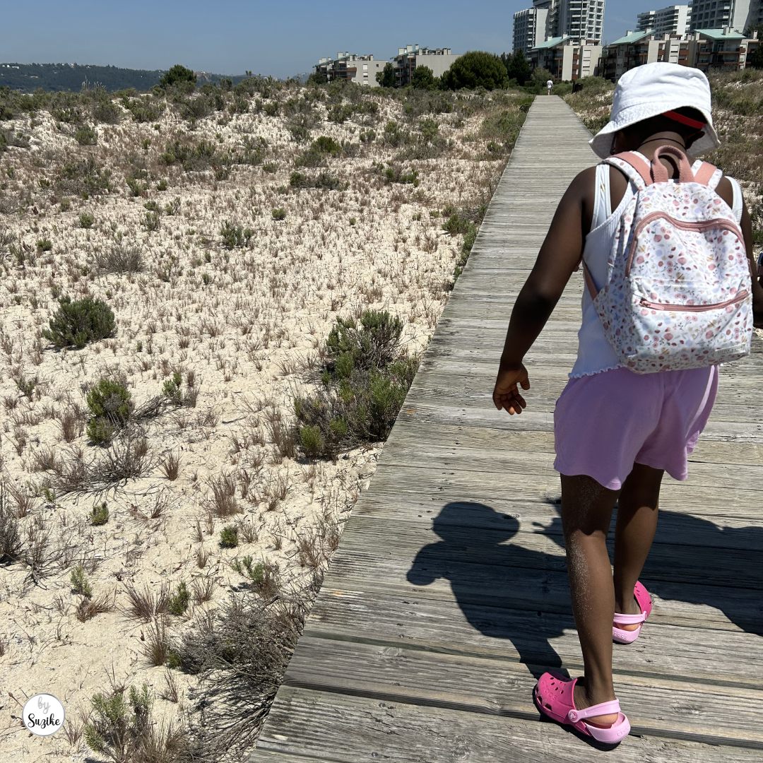 Kids’ activities before parents go on holiday with a child walking on a wooden beach path during a summer family day out.