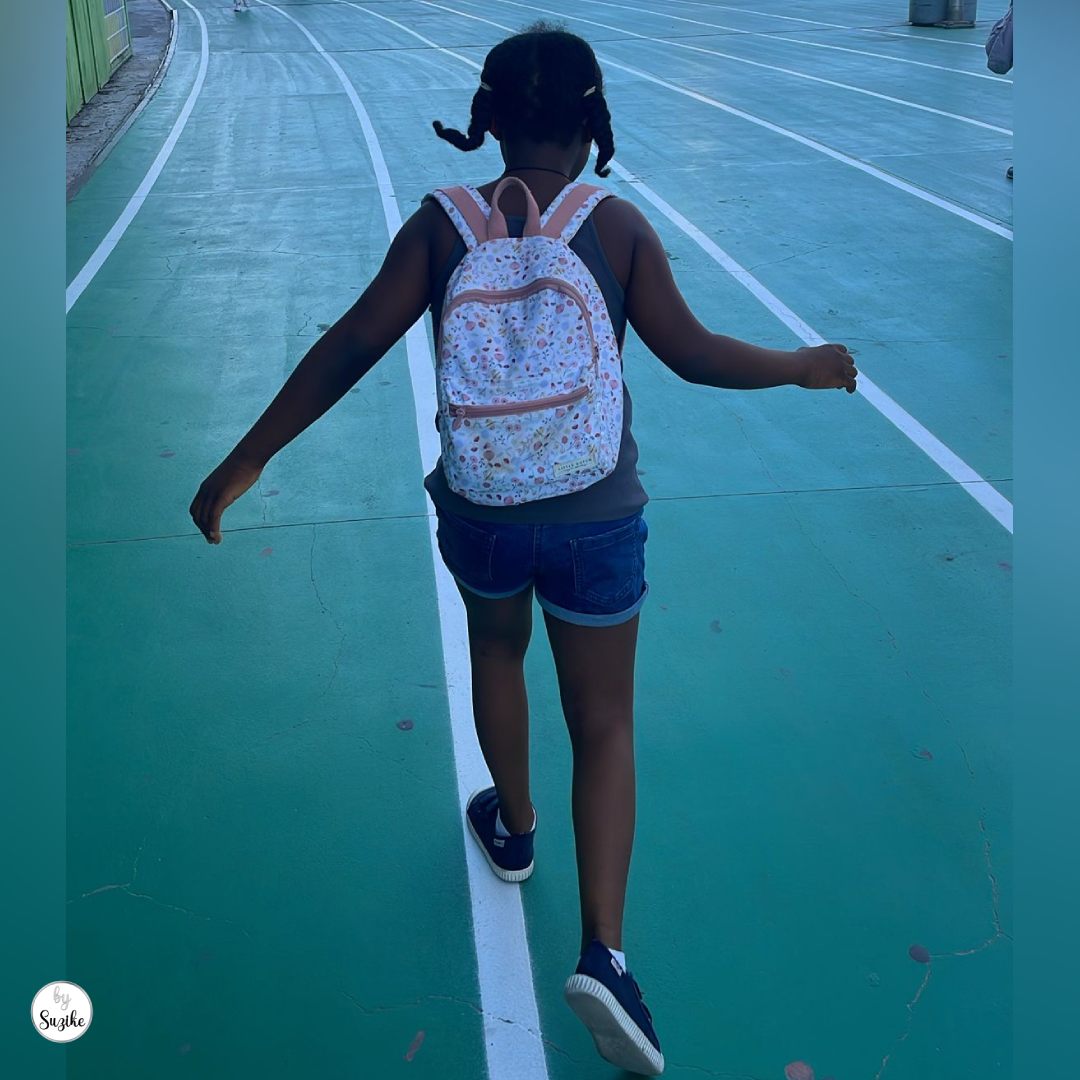 Kids’ activities before parents go on holiday with a child walking on an outdoor sports court during a simple summer activity.