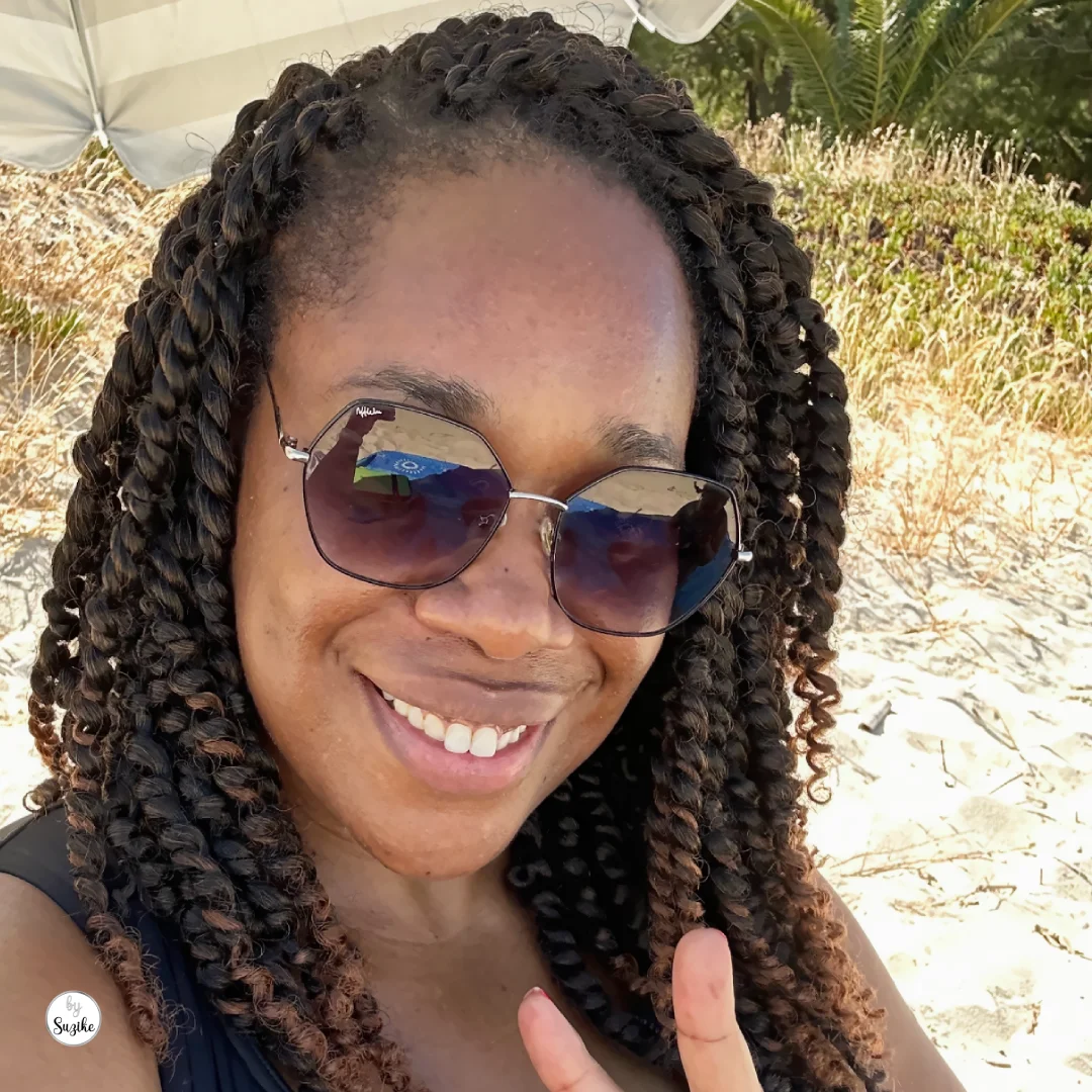 Woman smiling with the low-tide shoreline of Praia Fluvial do Rosário behind her.